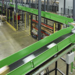 A fast moving incline conveyor transports parcels into the sorter at Clipper Logistics